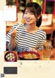 A woman sitting at a table with a plate of food and a drink.