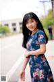 A woman in a blue floral dress posing for a picture.