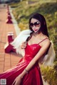 A woman in a red dress and sunglasses posing for a picture.