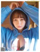 A woman in a blue hoodie is posing for a magazine.