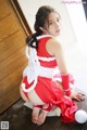 A woman in a red and white outfit sitting on the floor.