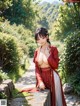 A woman in a red kimono sitting on a stone wall.