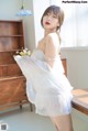 a woman in a white dress standing next to a table