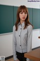 A woman standing in front of a blackboard in a classroom.