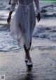 A woman in a white dress walking on the beach.