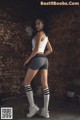 A woman in a white tank top and gray shorts holding a skipping rope.