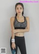 A woman in a sports bra top and leggings holding a water bottle.