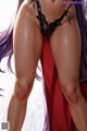 A woman in a black bikini with purple hair and a red cape.